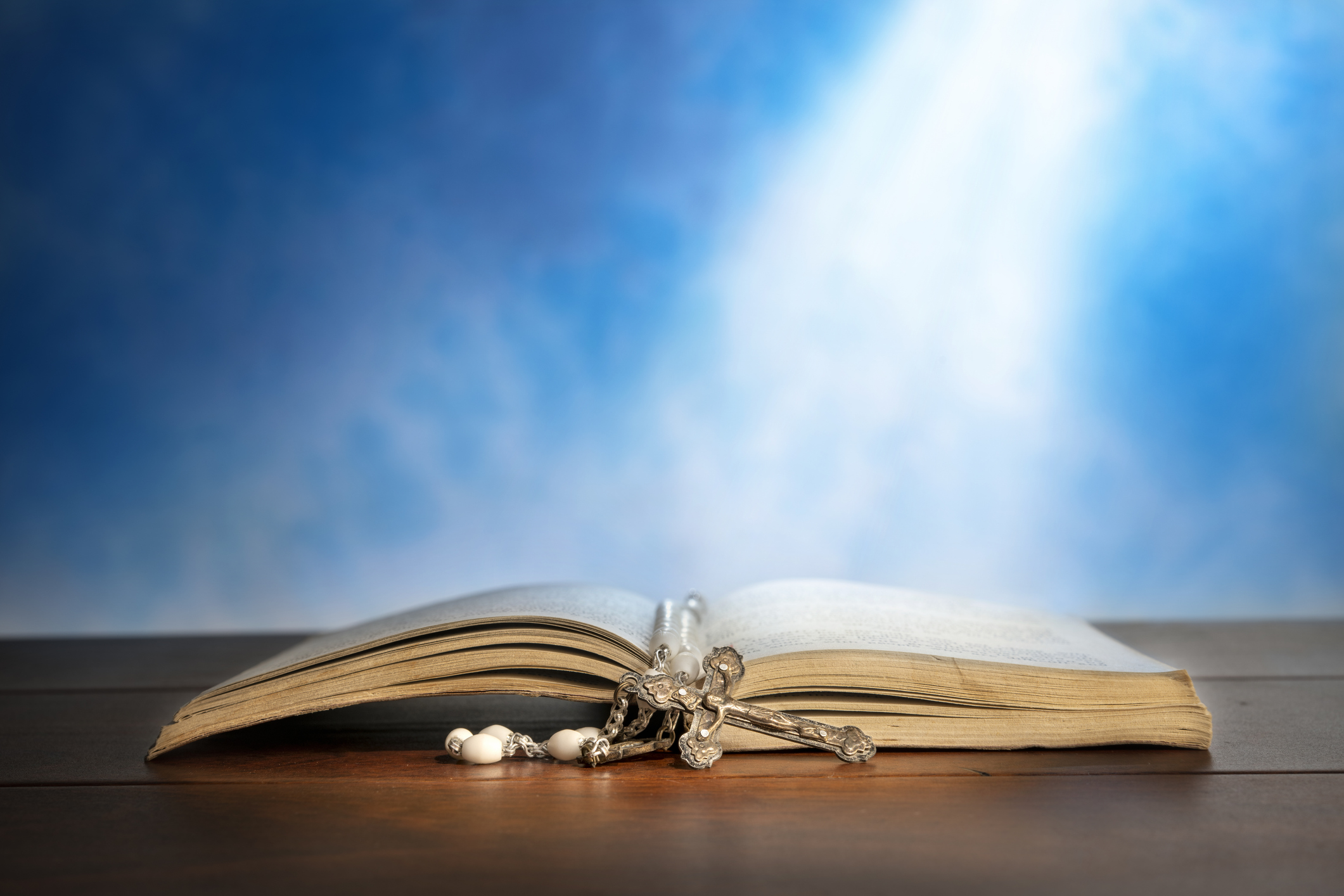 Bible and Rosary under light